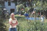 Debt Management image: Woman standing in sunny garden with family playing nearby
